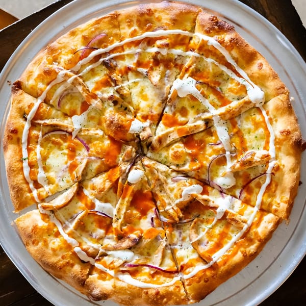 A Volare Restaurant pizza, topped with chicken, red onion, buffalo sauce, and a ranch drizzle.