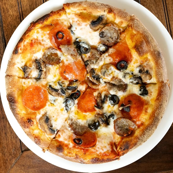 Volare Restaurant's pepperoni, sausage, mushroom, and olive pizza on a white plate.