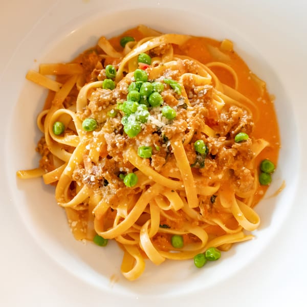 Volare Restaurant's linguine pasta with meat sauce, green peas, and grated cheese.