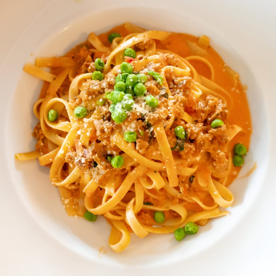 Volare Restaurant's linguine pasta with meat sauce, green peas, and grated cheese.